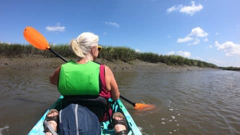 Kayaking On Murky Inlet With Orange Paddles And White Puffy